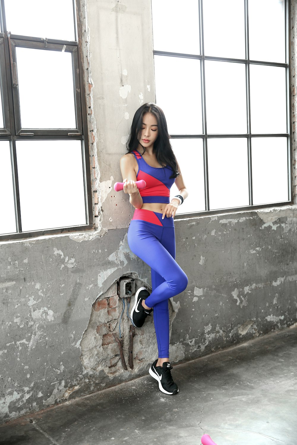 woman in blue leggings and black shoes sitting on concrete wall