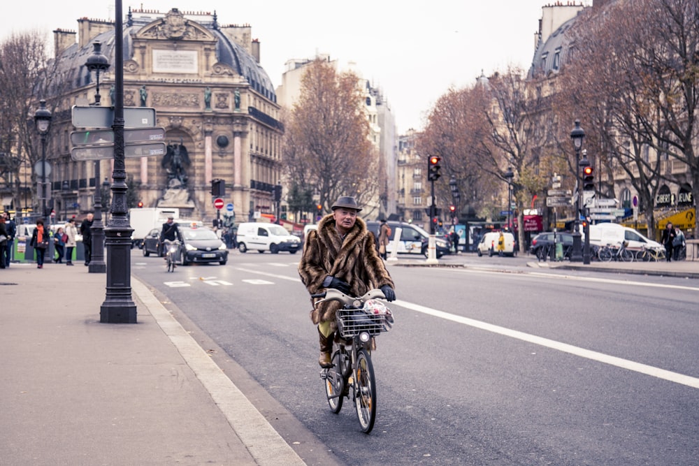 woman in brown coat riding bicycle on road during daytime