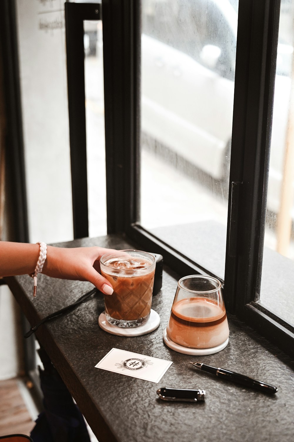 person holding clear plastic cup with brown liquid