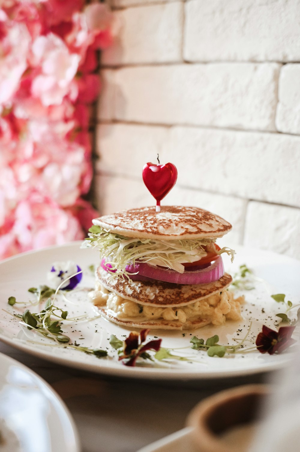 burger with tomato and lettuce on white ceramic plate