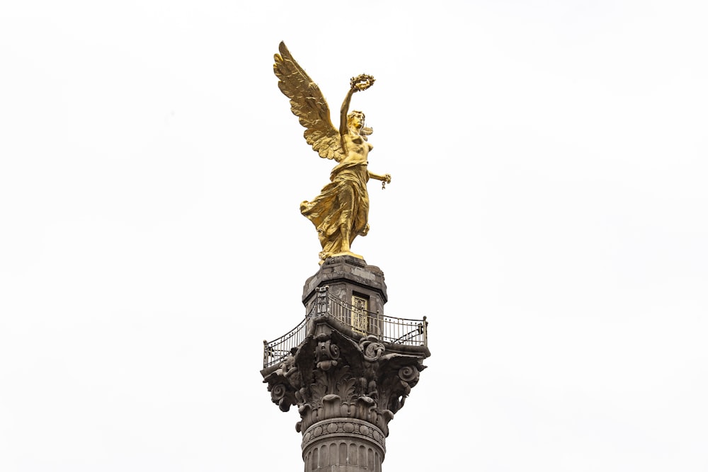 estátua do anjo dourado sob o céu branco durante o dia