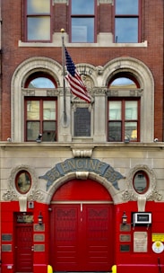 a red fire hydrant sitting in front of a fire station