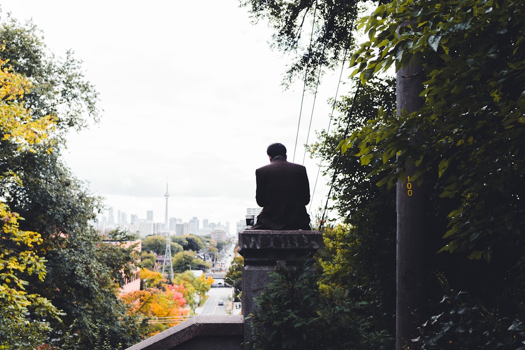 man in black jacket sitting on concrete bench during daytime