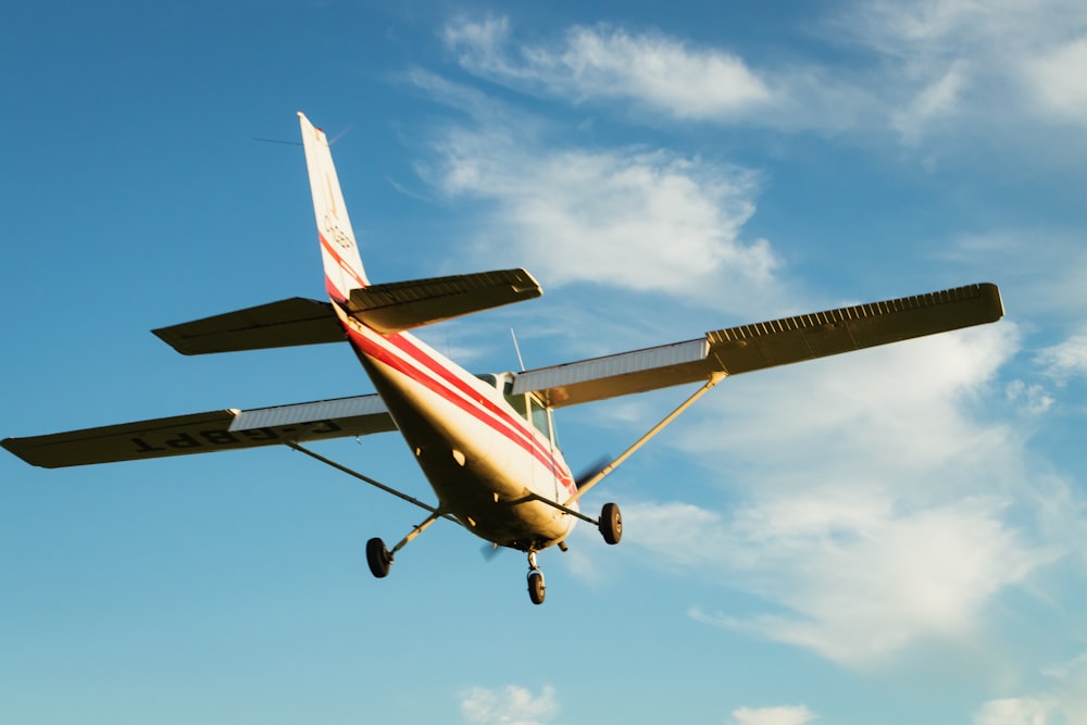 white and red airplane flying under blue sky during daytime