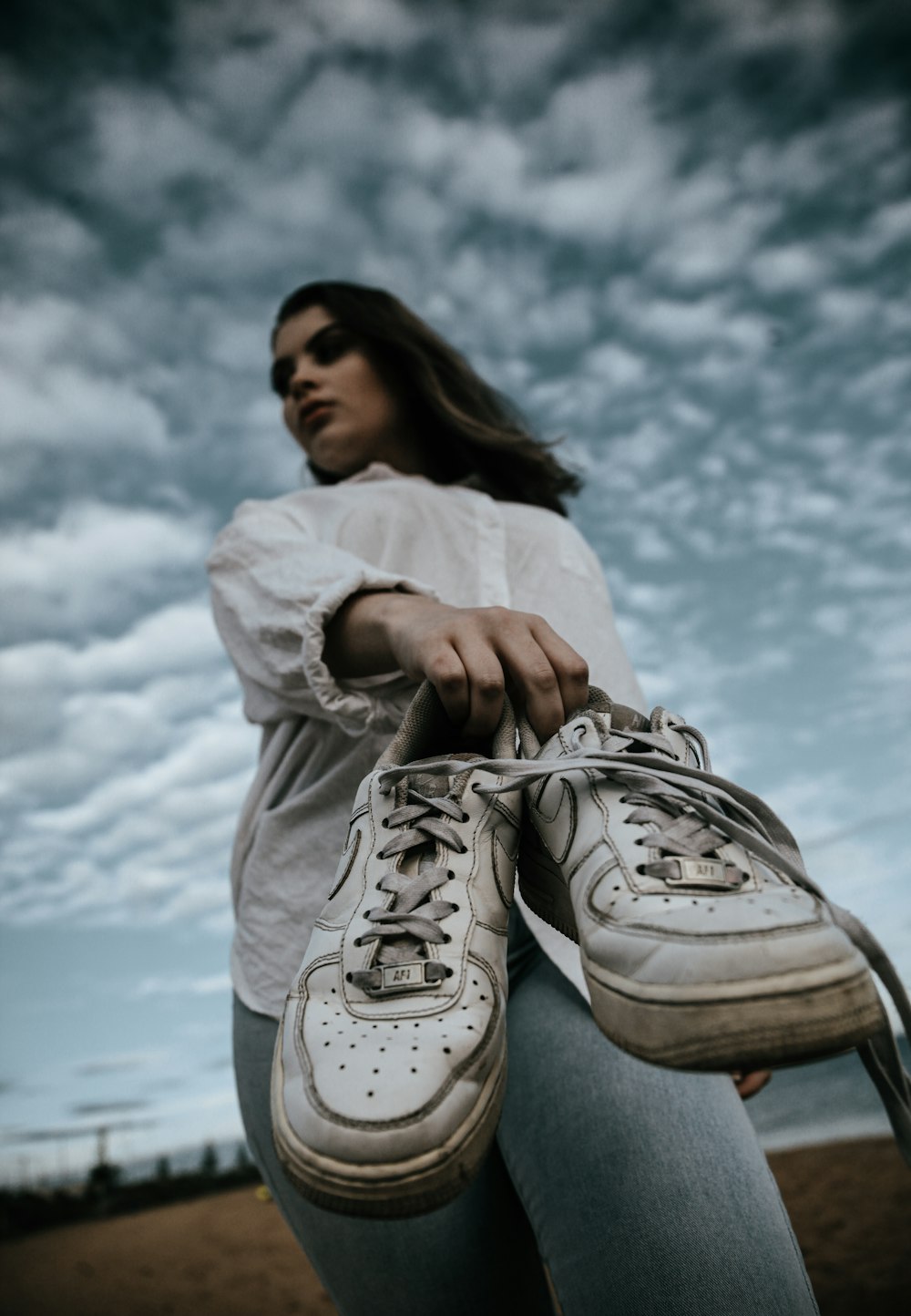 woman in white long sleeve shirt and gray pants sitting on gray rock