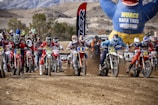 Group of motocross riders preparing for a race at sunset.