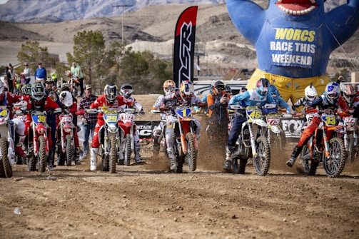 Group of motocross riders preparing for a race at sunset.