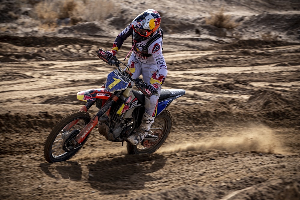 man in blue and white motorcycle suit riding motocross dirt bike on brown sand during daytime
