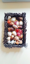 A rustic seashell mosaic with soft ivory and sandy beige tones, arranged on a wooden frame