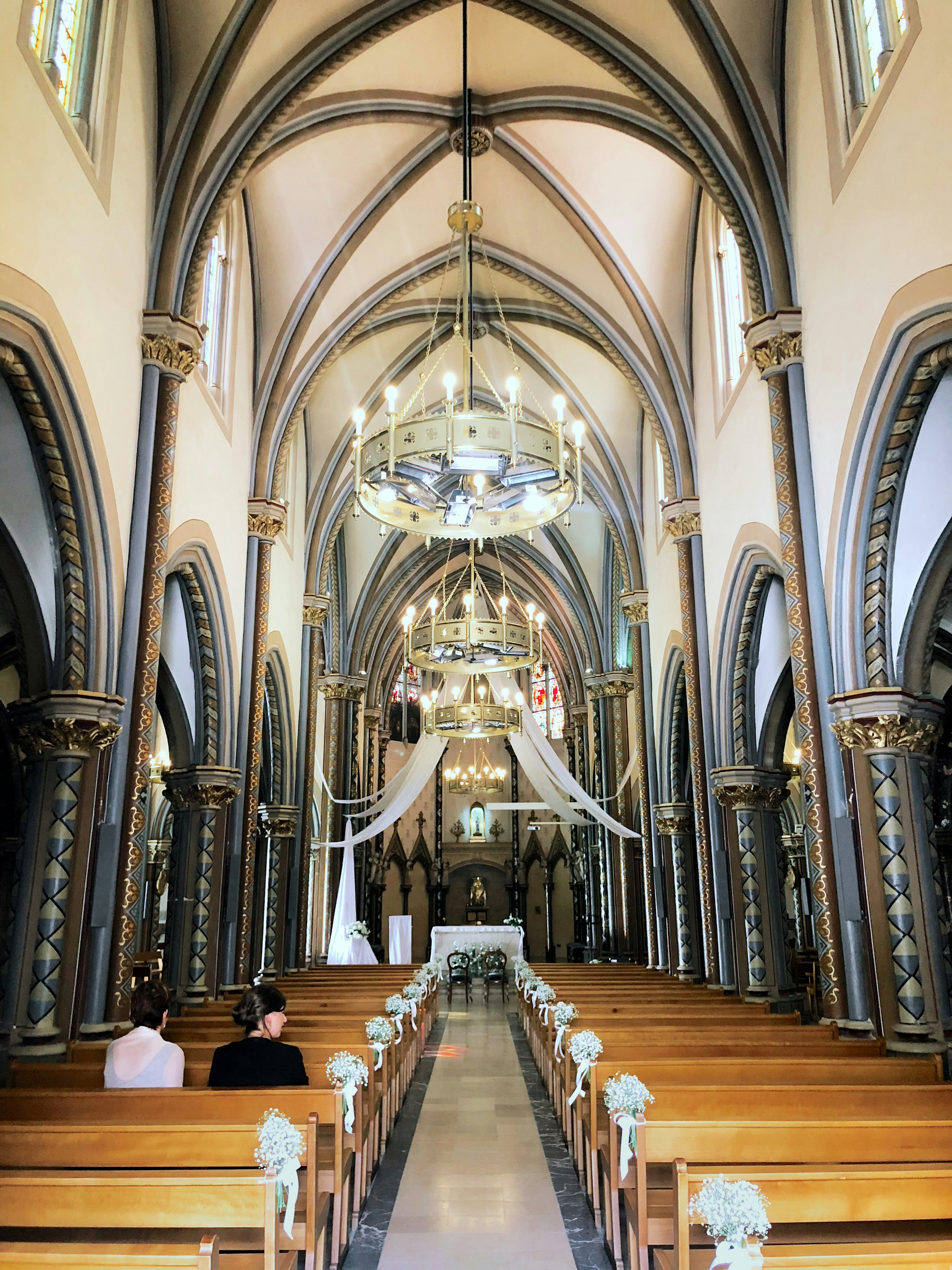 The French church, Notre Dame de Bon Encontre in Agen, France preparing for a wedding with flowers on each pew.