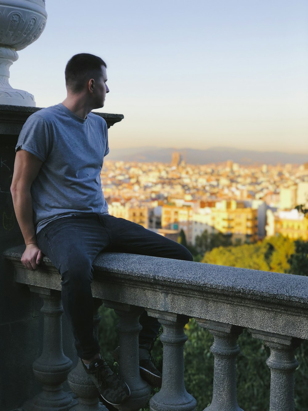 man in gray crew neck t-shirt and blue denim jeans sitting on gray concrete bench