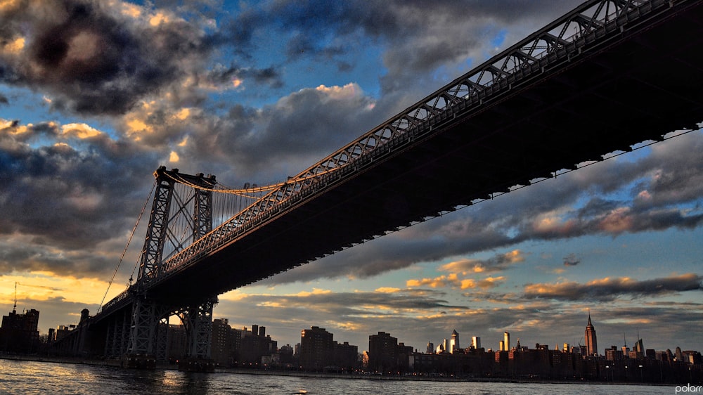 silhouette of bridge under cloudy sky during daytime