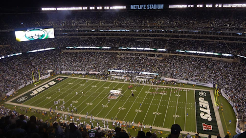 A vibrant LED panel lighting up a packed football stadium during a night game.