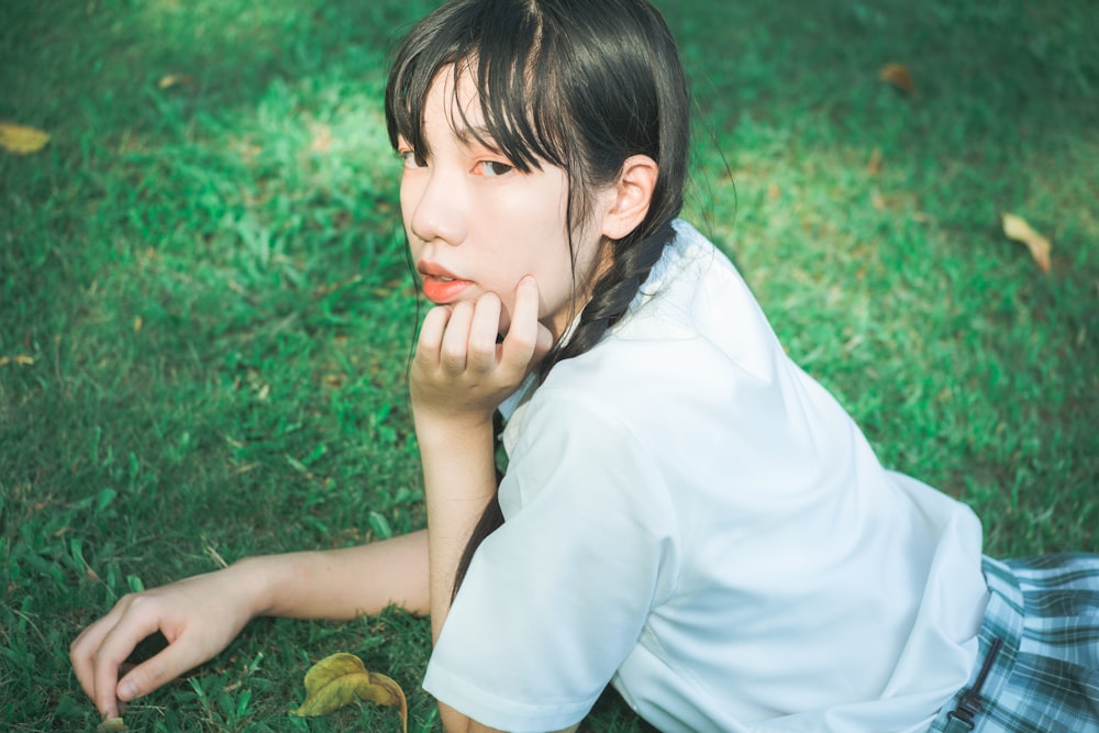 girl in white shirt lying on green grass