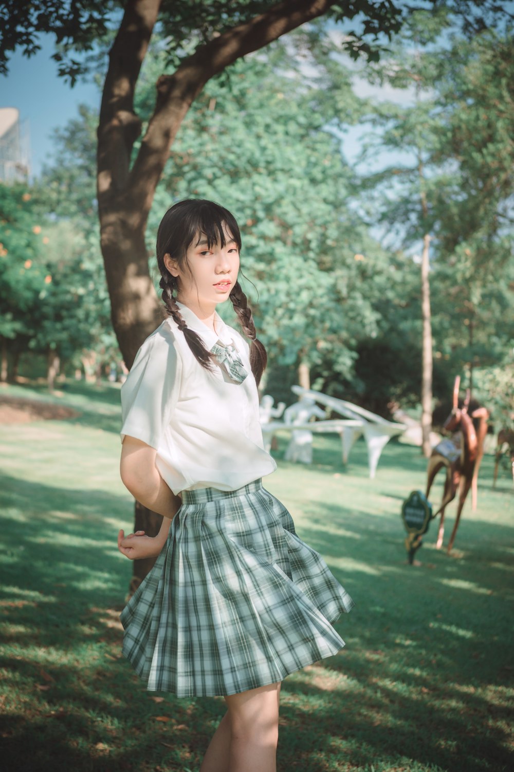 woman in white shirt and black and white plaid skirt standing on green grass field during