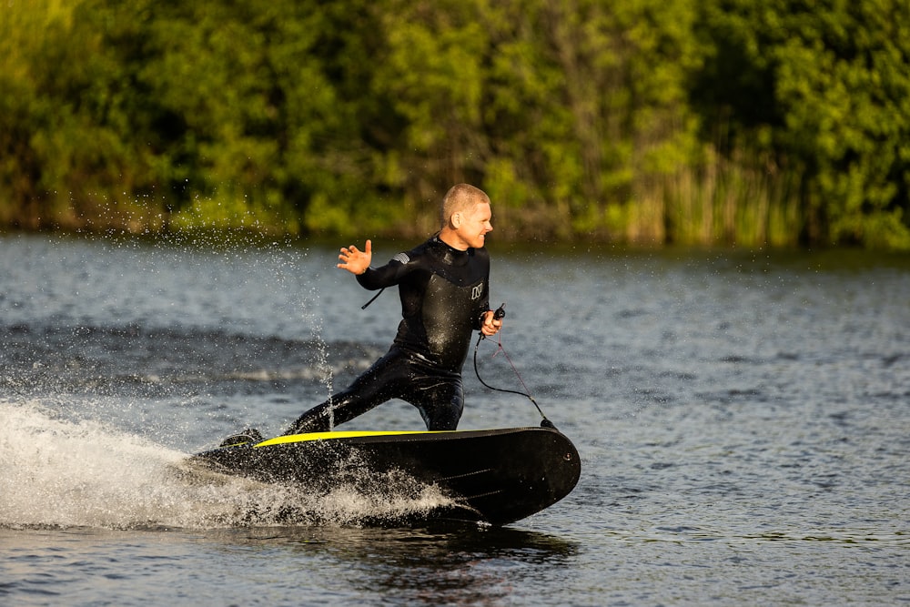 man in black wet suit riding on black and white boat during daytime