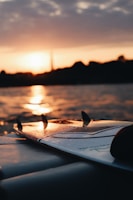 A vibrant surfboard resting on the beach at sunset.