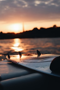 Close-up of a surfboard resting on golden sand with ocean waves in the background.