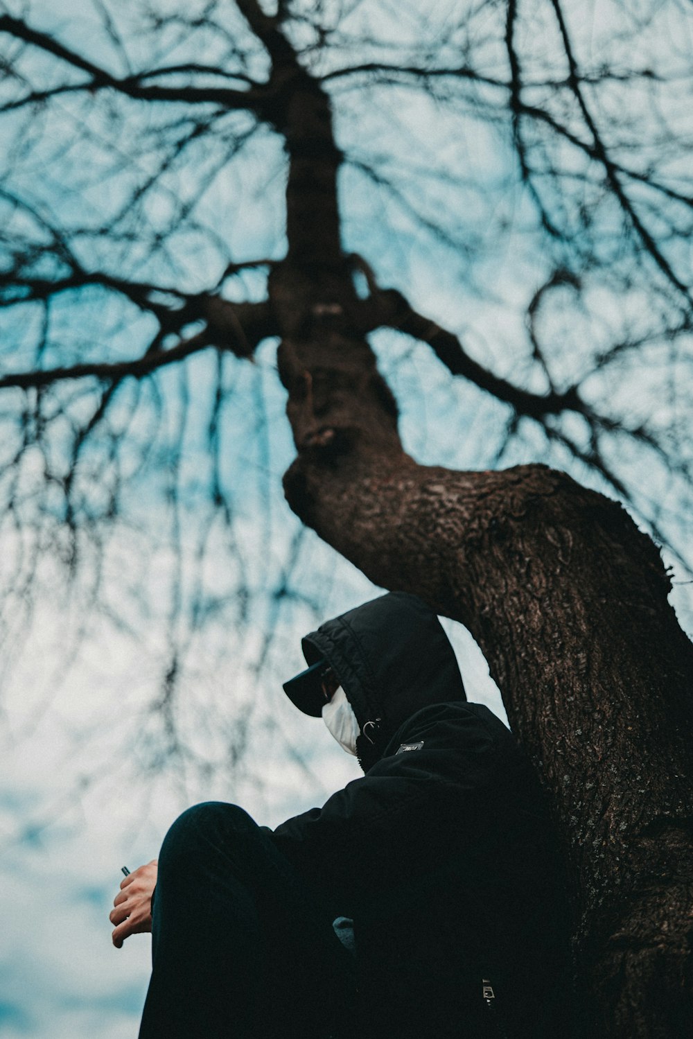 man in black jacket and black pants standing near brown tree during daytime