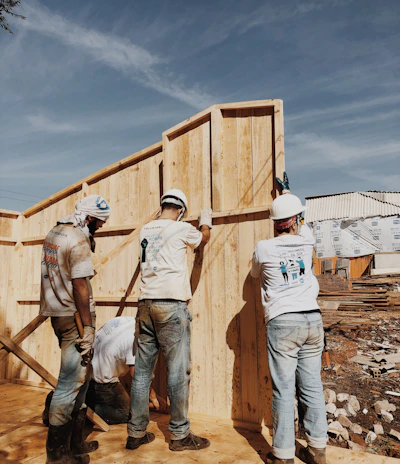 A skilled construction team working together on a modern villa foundation under a clear blue sky.