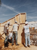 Workers collaborating on a construction site under a clear blue sky.