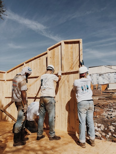 A construction site with workers collaborating on a building project under a clear blue sky.