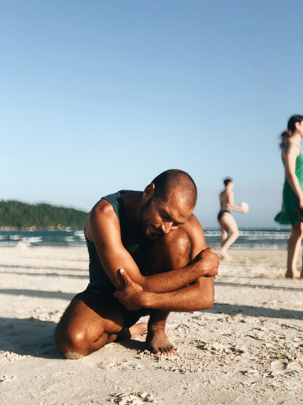 homme en short noir embrassant femme en débardeur noir sur la plage pendant la journée