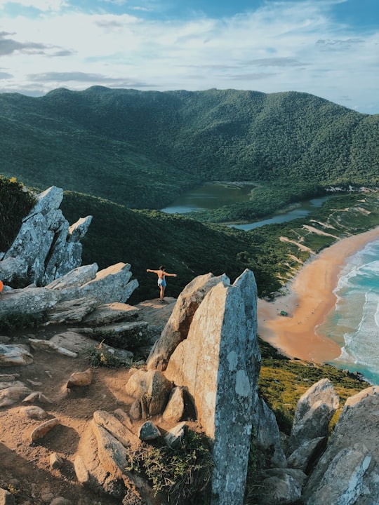 person standing on rock near body of water during daytime in Lagoinha do Leste Brasil