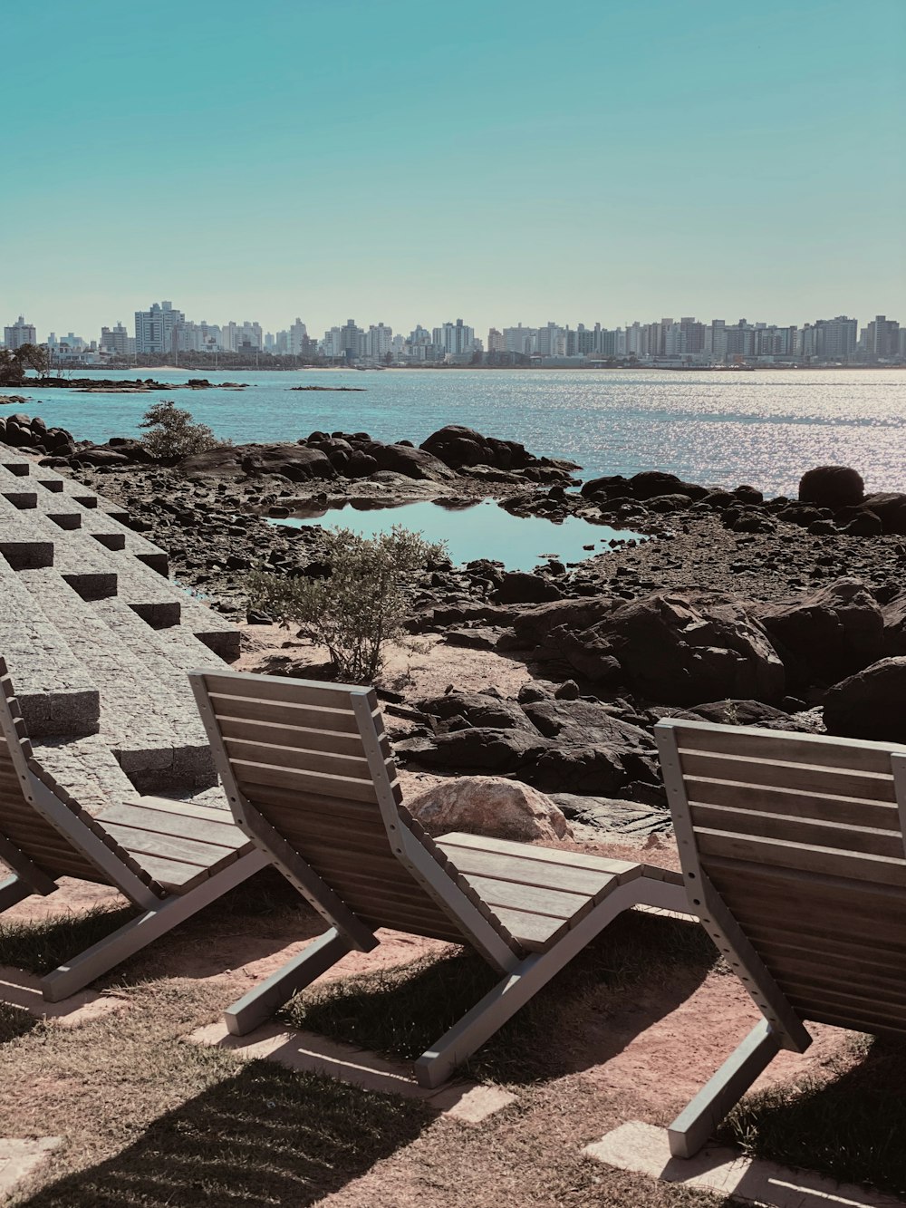 brown wooden bench on gray rocky shore during daytime