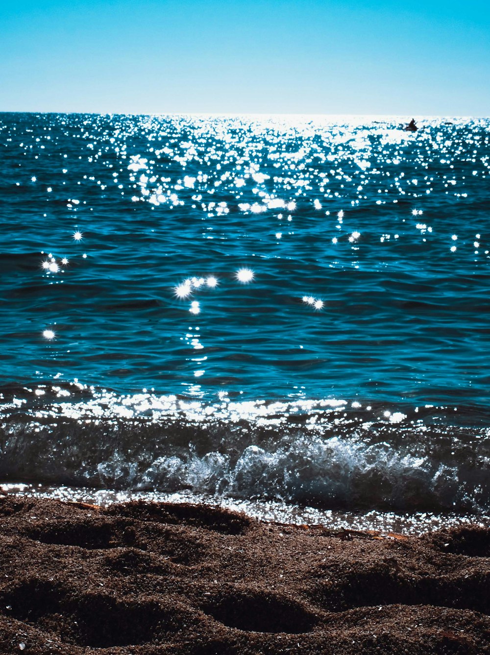 Olas de agua sobre arena marrón durante el día