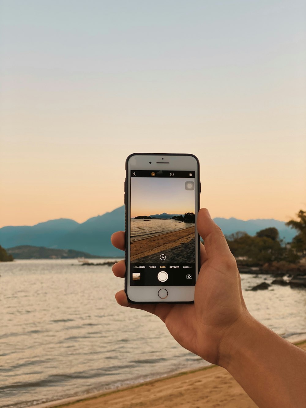 a person taking a picture of a lake with a cell phone