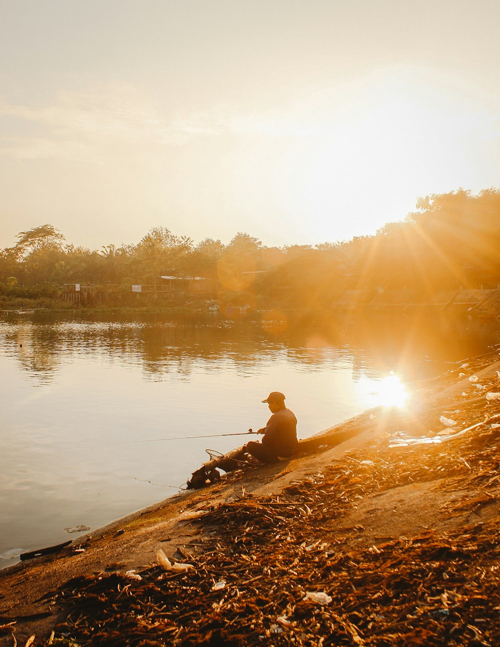 man in brown jacket sitting on brown rock near body of water during daytime