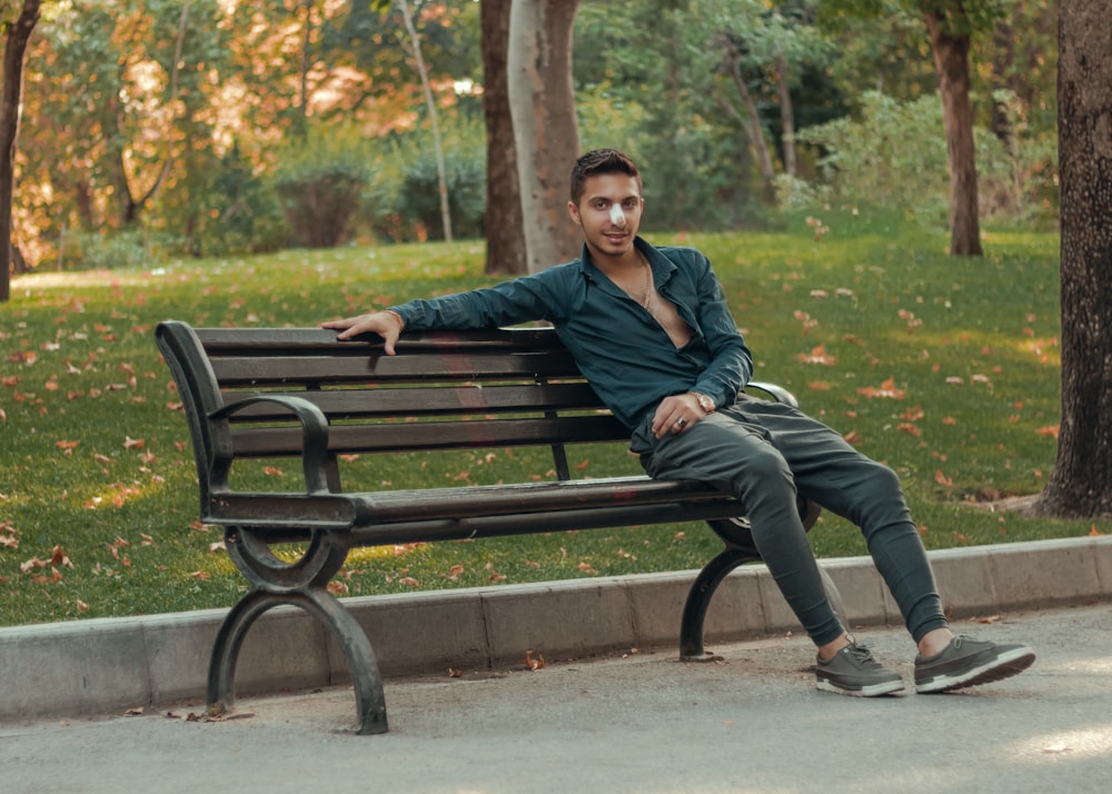 man in black jacket sitting on brown wooden bench