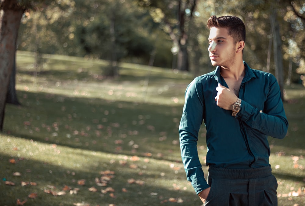 man in blue dress shirt and black vest standing on green grass field during daytime