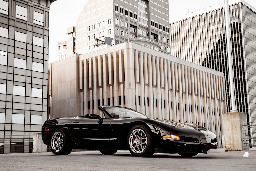 a black sports car parked in front of a tall building