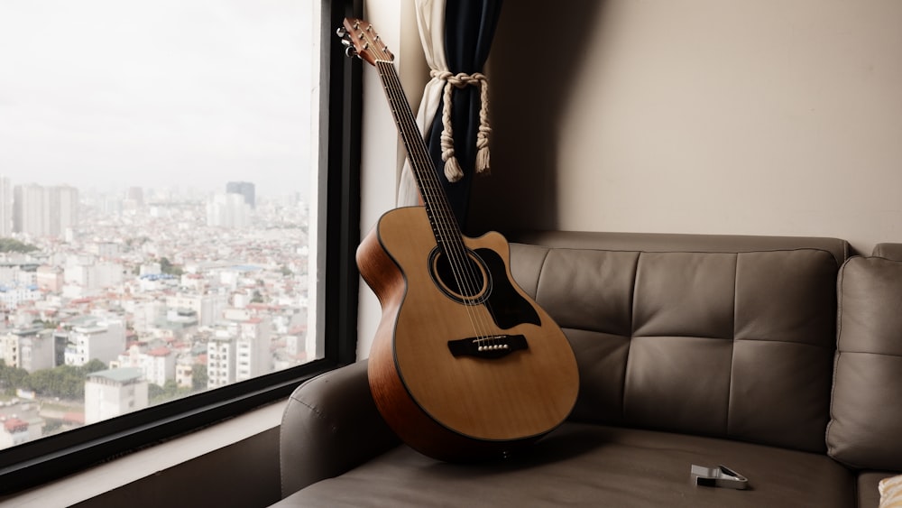 brown acoustic guitar on black padded couch
