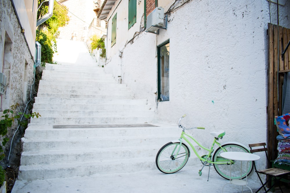 green bicycle parked beside white concrete building during daytime
