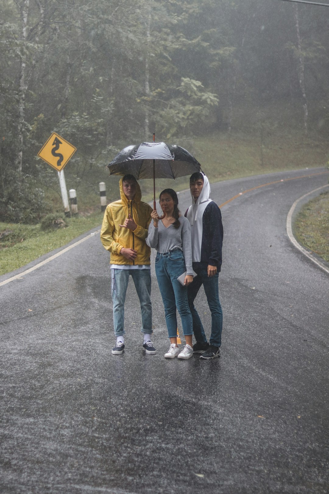 man and woman holding umbrella walking on the road during daytime