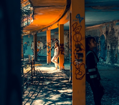 Two urban explorers discussing plans while standing near a graffiti-covered wall in an abandoned urban site.
