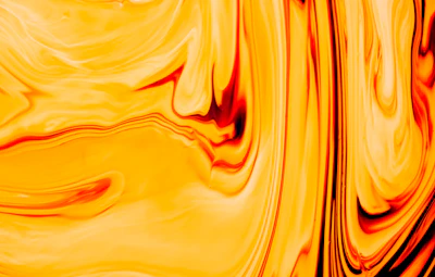 Bright yellow and orange hair dye blending together in a swirl pattern inside a mixing cup.