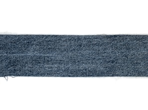 A rectangular strip of blue denim fabric with a textured pattern. The edges appear slightly frayed, and the denim has a deep blue color with a subtle variation in the weave.