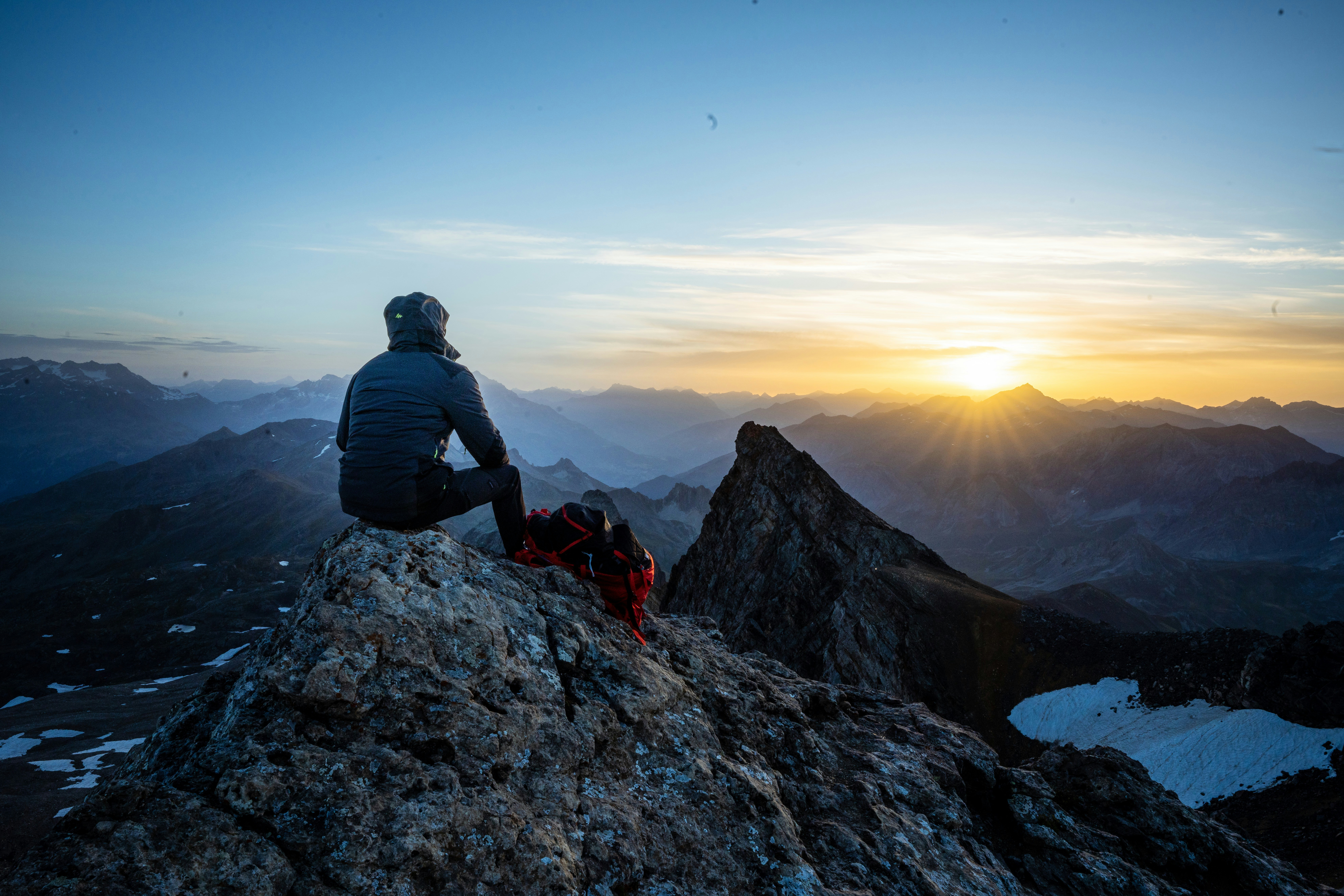 homme en veste noire assis sur le rocher pendant la journée