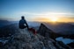 man in black jacket sitting on rock during daytime