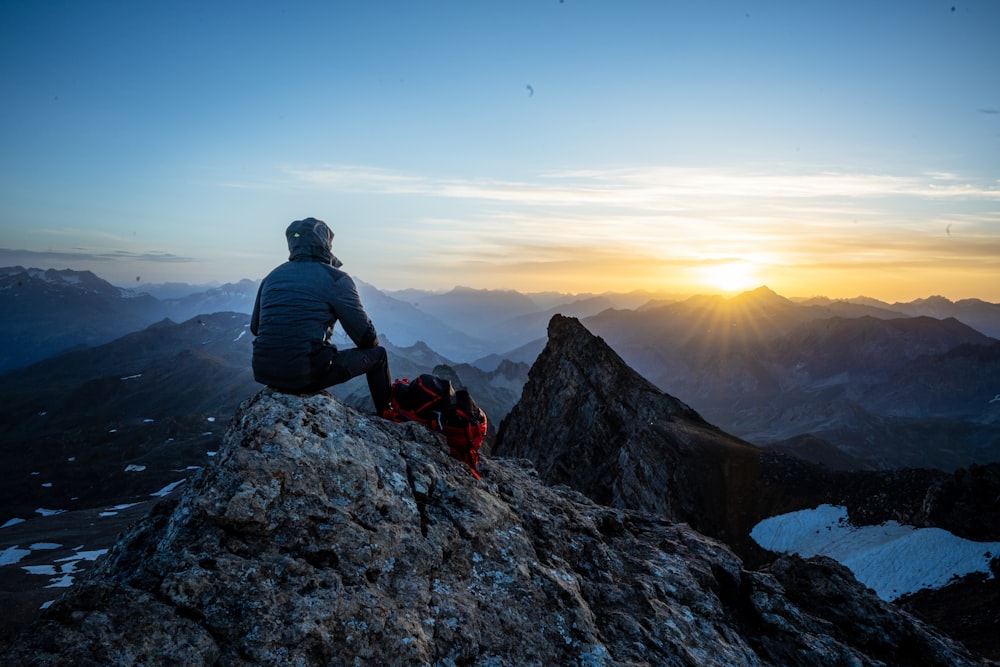 man in black jacket sitting on rock during daytime