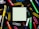 A square piece of blank paper is surrounded by various colorful office supplies including pens, paper clips, and thumbtacks, all placed on a black background. The items are arranged symmetrically around the paper, creating a neat and organized look.