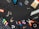 A variety of tools and items are arranged against a black background. These include a drill, a paintbrush, screws, drill bits, pliers, an eraser, some markers, a measuring tape, a spool of twine, and several other small hardware items.