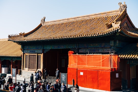 people walking on street near red concrete building during daytime in The Palace Museum China