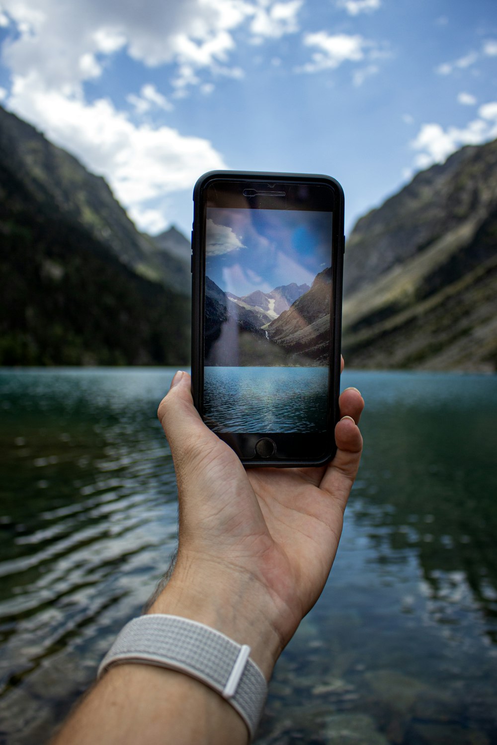 person holding black smartphone taking photo of lake during daytime