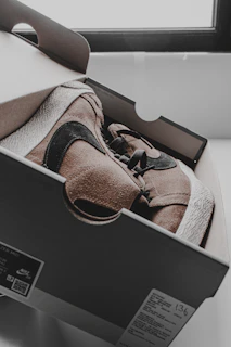 Elegant sneaker box opened to reveal a pristine pair, set against a clean black backdrop.