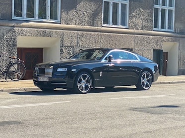 A sleek car with a driver waiting beside it ready for rental service.